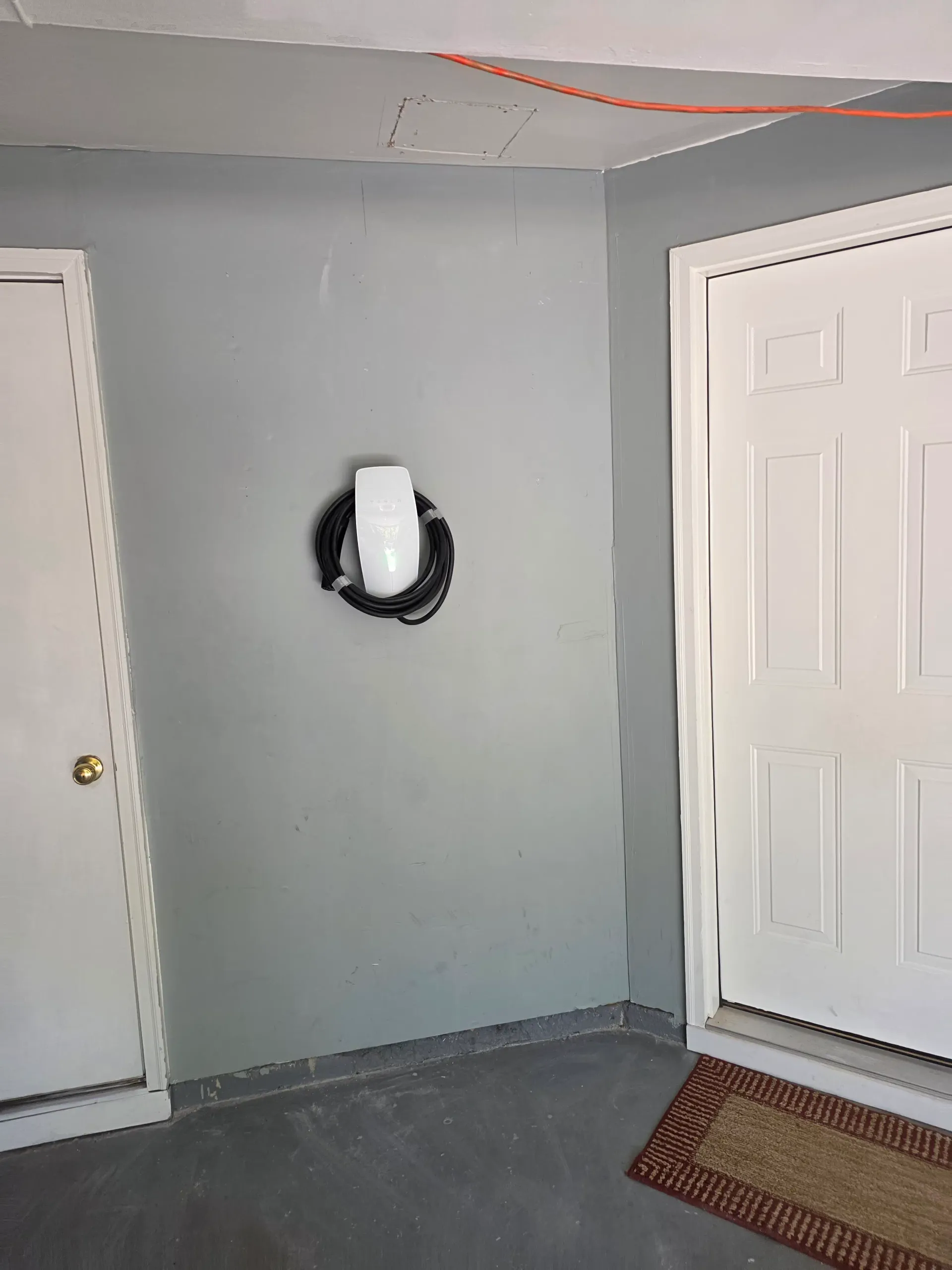 Tesla Wall Connector mounted on a garage wall in Ashburn, Virginia, with the charging cable neatly coiled