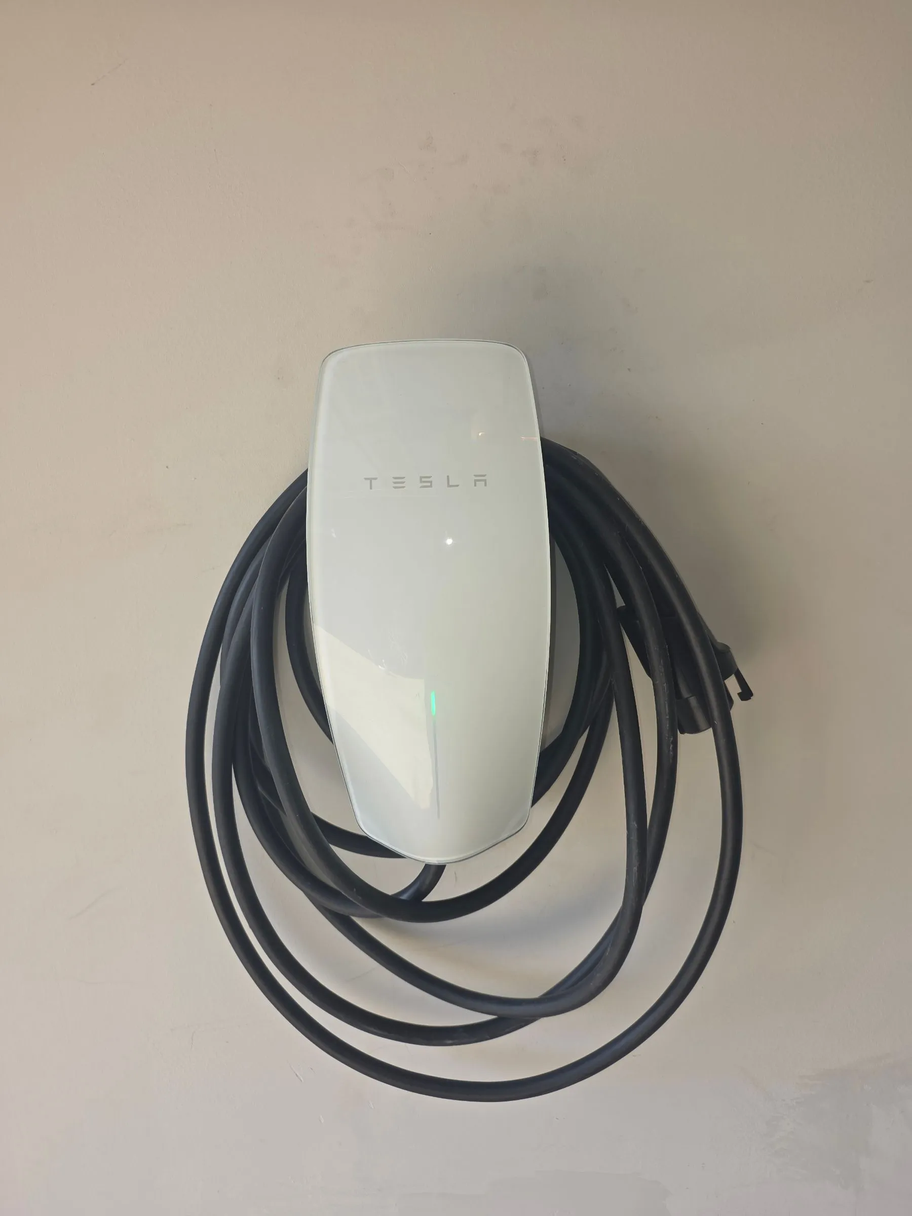 Tesla Wall Connector mounted on a residential wall in Fairfax County, Virginia, with the charging cable coiled