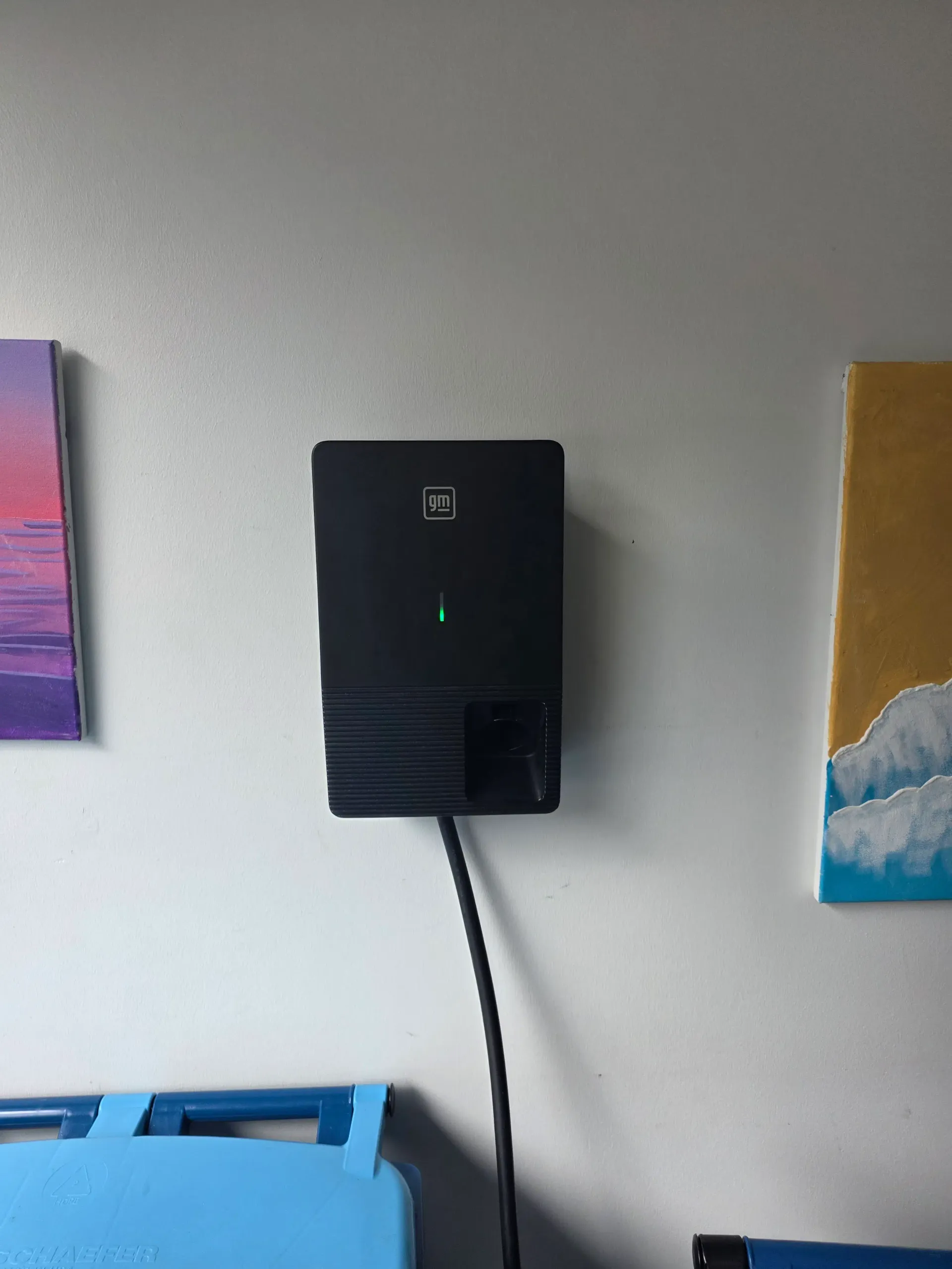 GM EV charger mounted on a garage wall with its status light illuminated