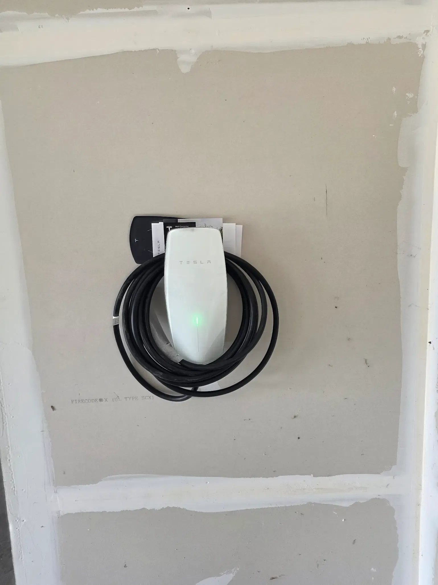 Tesla Wall Connector mounted on a residential wall in Leesburg, Virginia, with the charging cable coiled